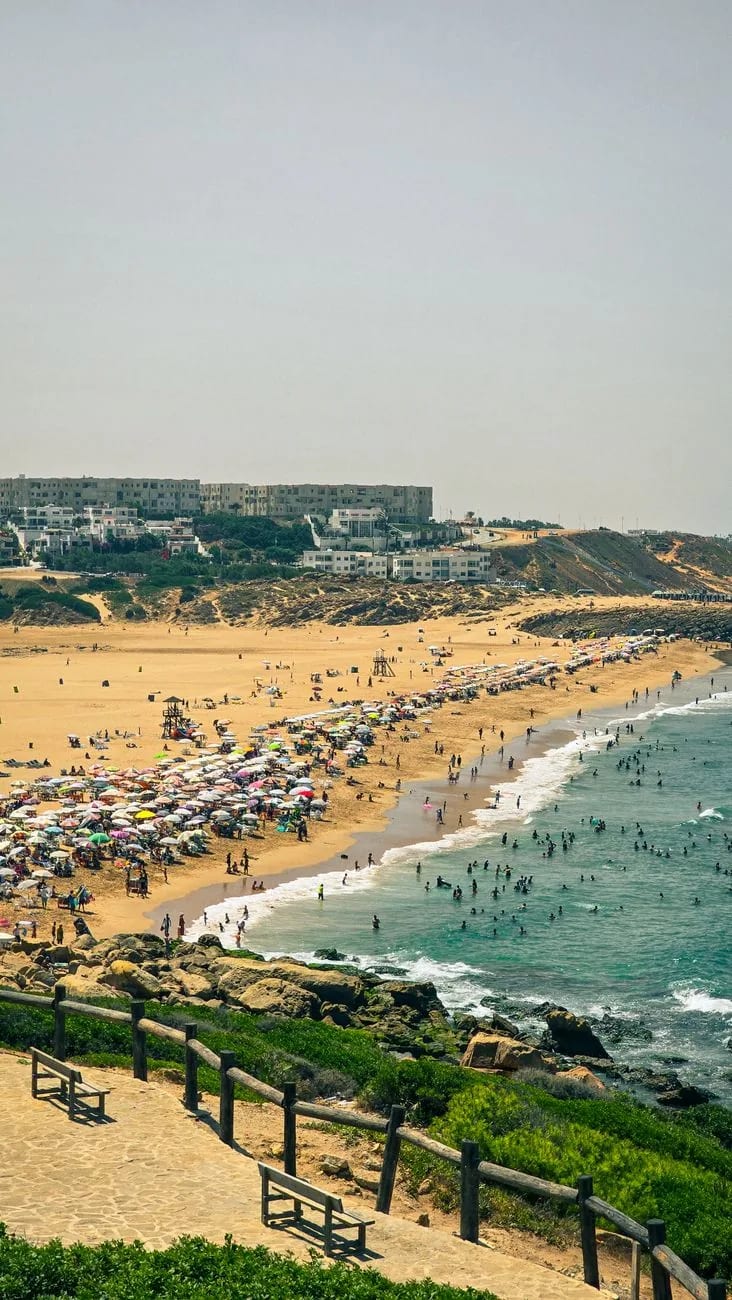 Plage d’Agadir en croissant, parasols et baigneurs, ville blanche derrière