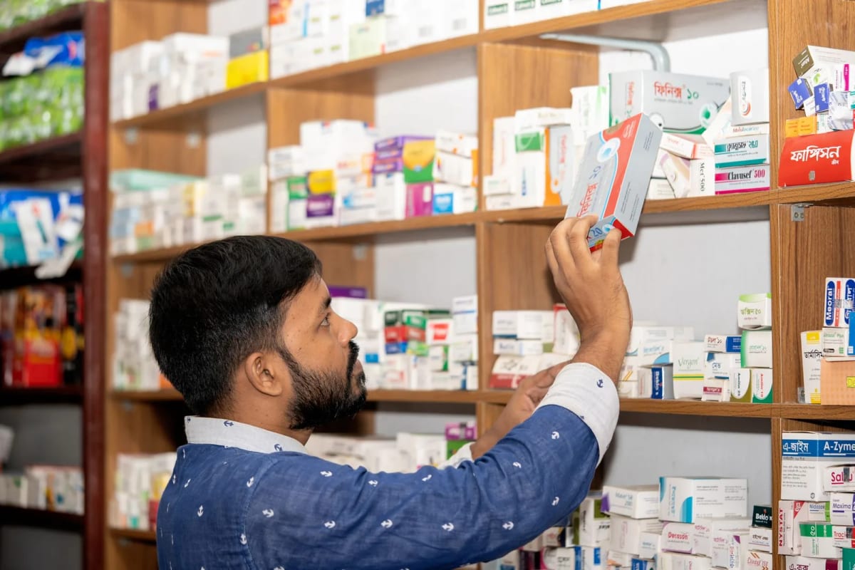 Pharmacien attrapant une boîte de médicaments sur les rayonnages de son officine