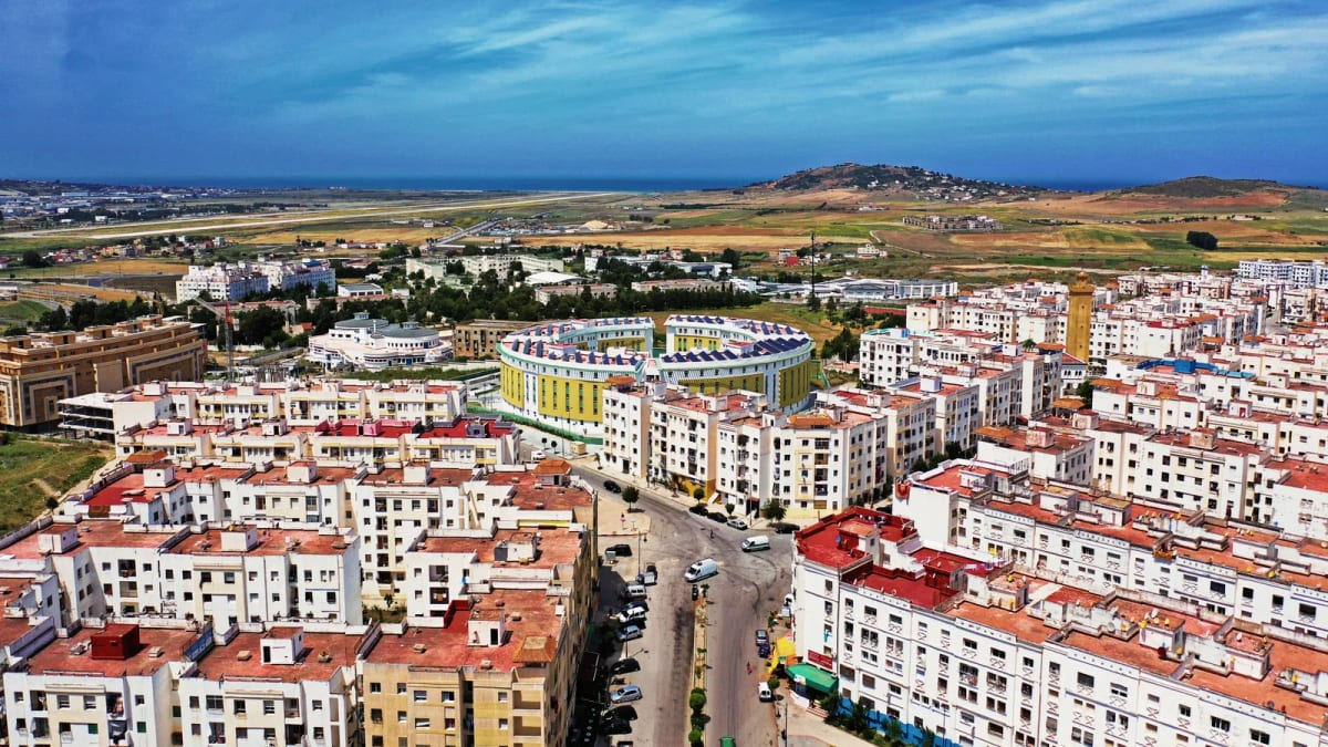 Vue aérienne d’un quartier résidentiel de Tanger, immeubles blancs aux toits rouges et collines au loin