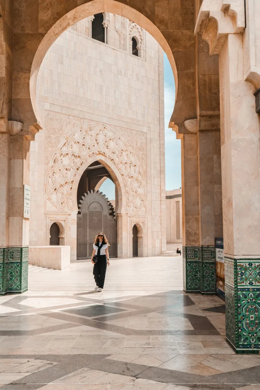 Galerie d’arcades en marbre de la mosquée Hassan II de Casablanca, silhouette d’une visiteuse