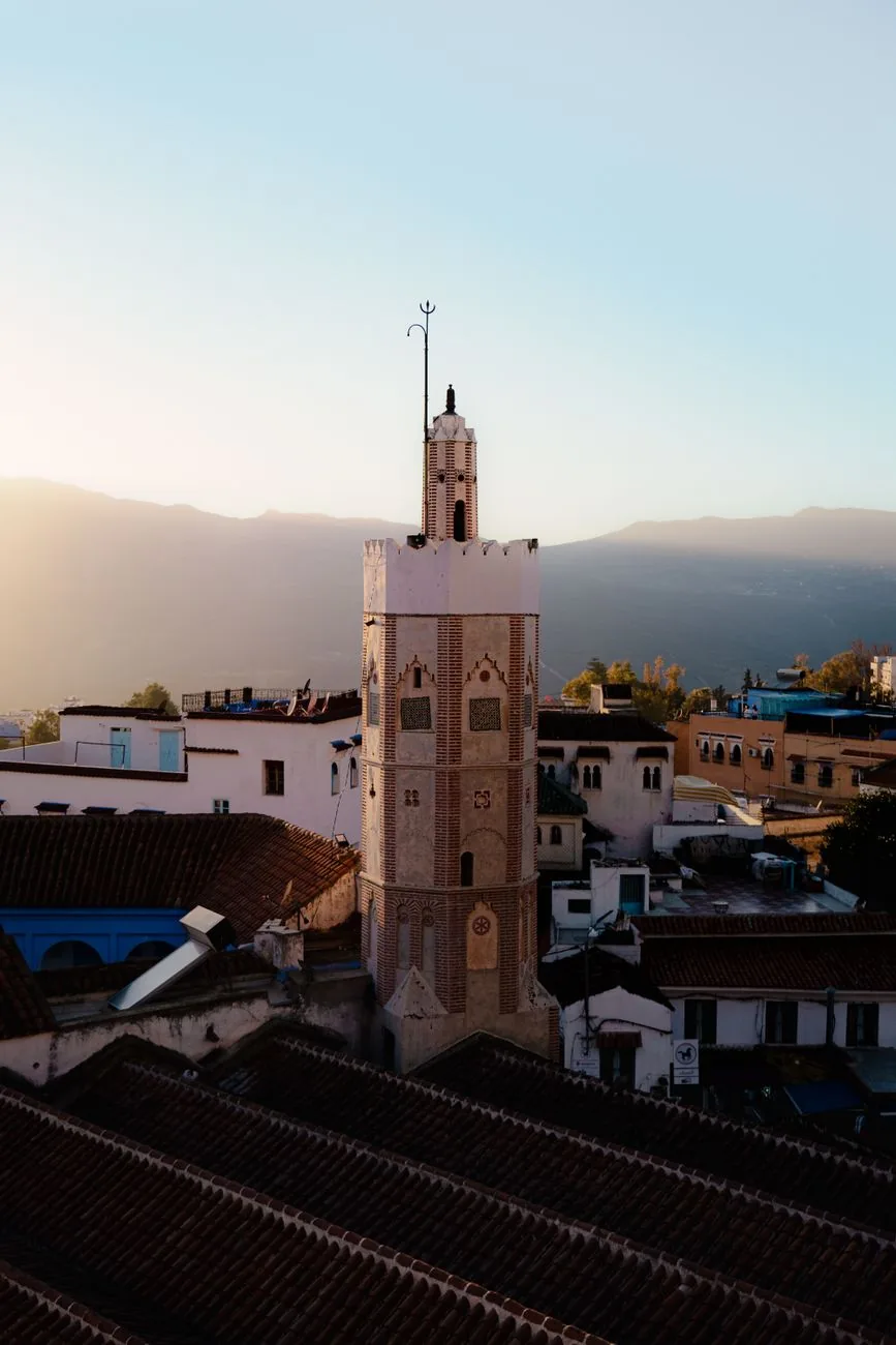 Minaret octogonal de la Grande Mosquée de Chefchaouen au-dessus des toits, montagnes du Rif derrière