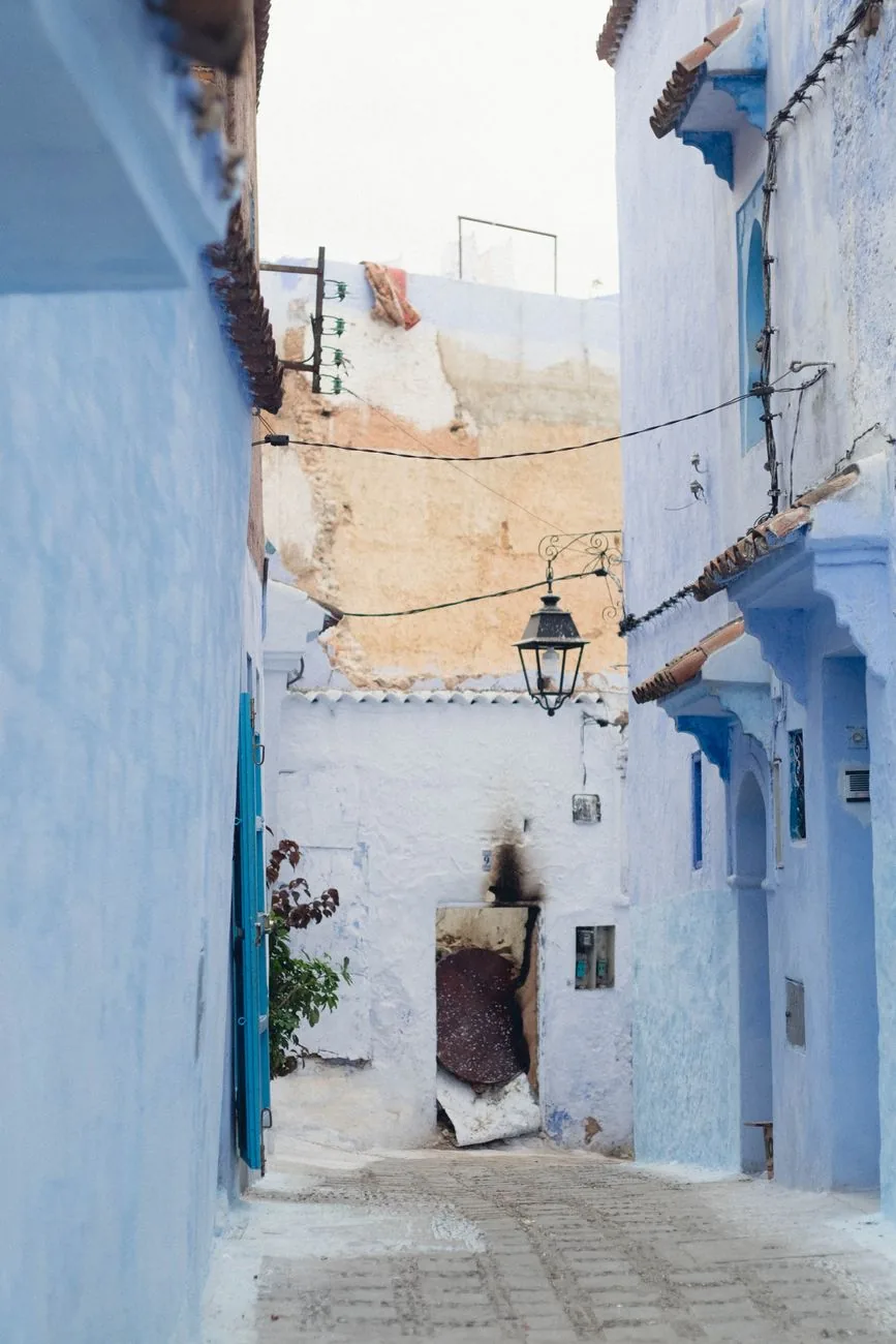 Ruelle bleue de Chefchaouen avec une lanterne de fer forgé et des portes peintes
