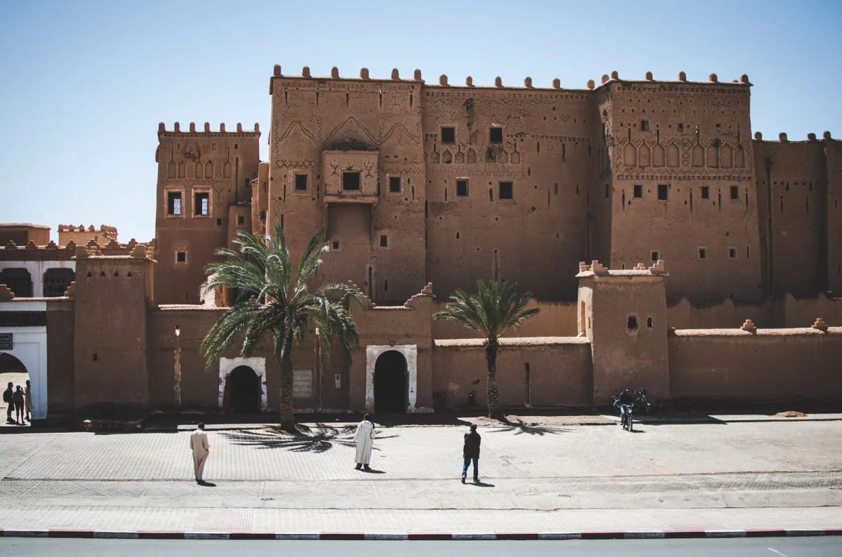 Façade en pisé de la kasbah Taourirt à Ouarzazate, tours crénelées et palmiers