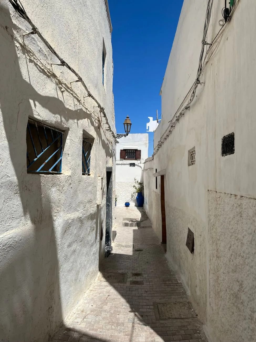Ruelle blanche en pente de la médina de Tanger, murs chaulés et portes bleues